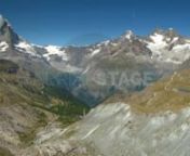 Tiefflug über karge Gletschermoräne / Flying low over the barren glacier of ZermattnnLuftaufnahme Stock Footage Clip von einem Tiefflug über Zermatter Gletschermoräne. Das Schweizer Wahrzeichen Matterhorn steht mit einem Hut am Horizont. Durch die stetige Klimaerwärmung gehen die Gletscher ständig zurück und man sieht beeindruckende Gletschermoränen sowie abgeschliffene Talsohlen und Talseiten. Die Luftaufnahme wurde mit dem Ecureuil B3 und dem kreiselstabilisierten Cineflex V14 System m